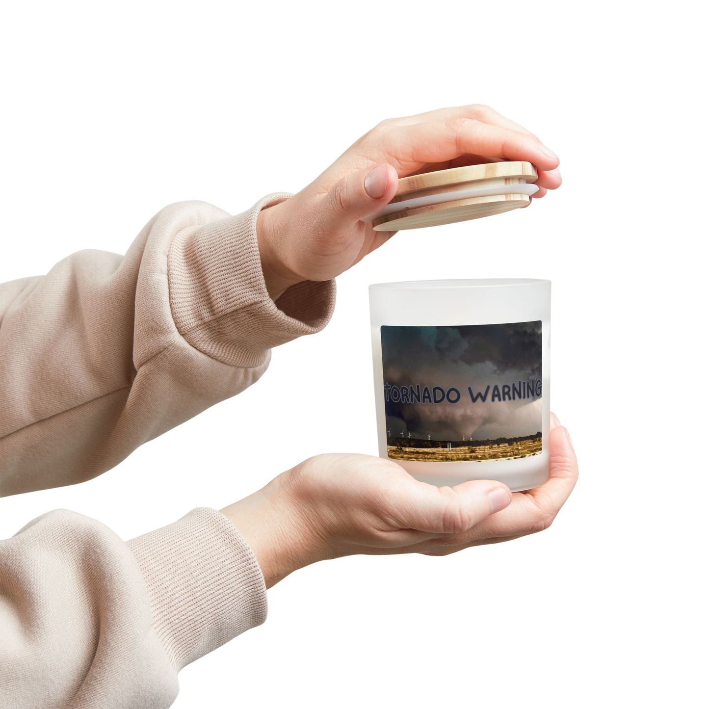 Frosted glass candle with "Tornado Warning" design held in hands, perfect for rustic decor and eco-friendly gifting.