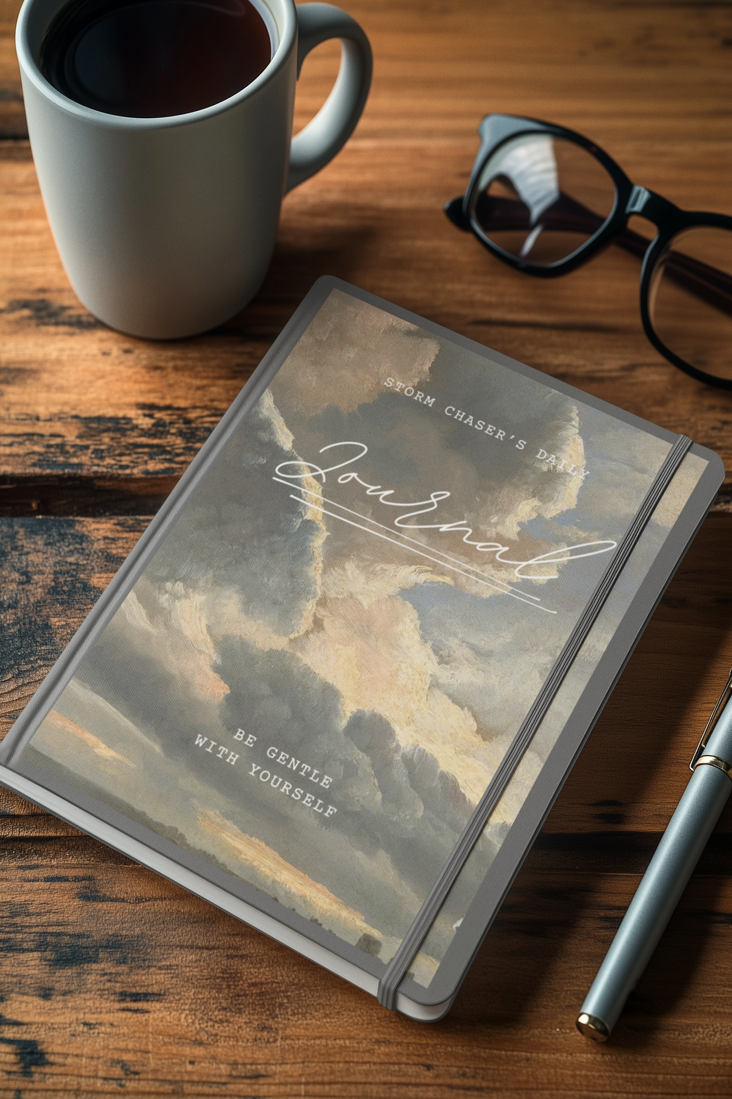 Storm Chaser's Daily Journal with stormy cover, coffee cup, and pen on wooden table.